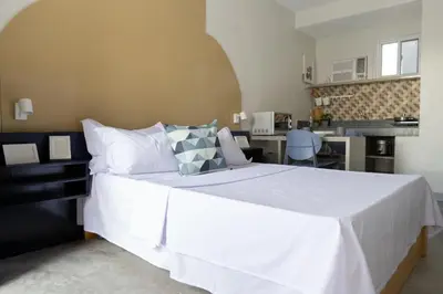 a bedroom with a large white bed and a kitchen at Hive Manila Guesthouse -Netflix,400mbps WI-FI in Bacoor