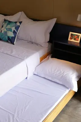 two beds with white pillows and a night stand at Hive Manila Guesthouse -Netflix,400mbps WI-FI in Bacoor