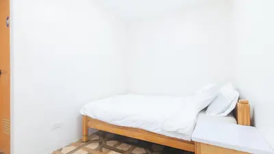 a bedroom with a white bed and a chair at RedDoorz @ Alquiza Residences Paranaque in Manila