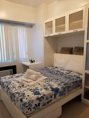 a bedroom with a bed with a blue and white comforter at Sea Residences Homey Condo by DNJ in Manila