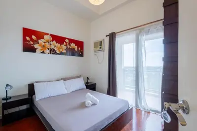 a bedroom with a bed and a large window at Raya P09 - Airport-Side Penthouse in Manila