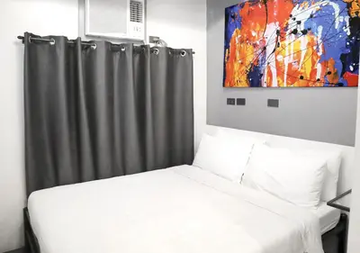 a bedroom with a bed and a painting on the wall at mySTAY Hotel BGC West in Manila