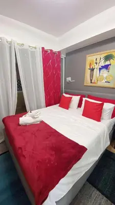 a bedroom with a large white bed with red pillows at Azure south urban beach resort near airport in Manila