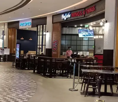 a person standing in a restaurant with tables and chairs at Marivic's Place at Air Residences Makati in Manila