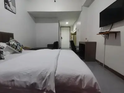 a bedroom with a large white bed and a flat screen tv at TemporaryHome -susan in Manila