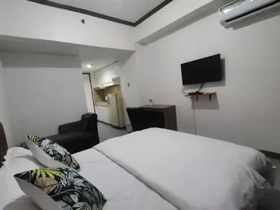a bedroom with a white bed and a flat screen tv at TemporaryHome -susan in Manila