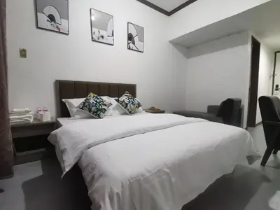 a bedroom with a large white bed and a chair at TemporaryHome -susan in Manila