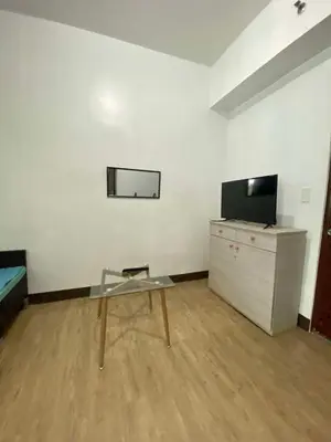 a room with a table and a tv on a dresser at staycation affordable in Manila