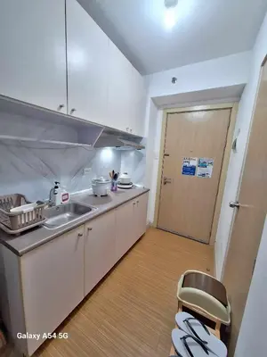 a kitchen with a sink and a chair next to a door at Stylish 1BR with Wifi and Queen size bed in Grace Res in Manila
