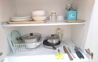 a kitchen shelf with dishes and utensils on it at Stylish 1BR with Wifi and Queen size bed in Grace Res in Manila