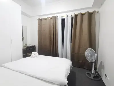 a bedroom with a white bed and a fan at Comfort Accommodation Services in Manila