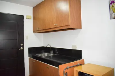 a kitchen with a sink and wooden cabinets at The Boni Tower by RSPL Manila City Center in Manila
