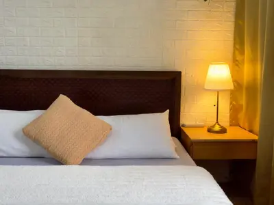 a bed with a pillow and a lamp on a table at Hannah’s Morning Sun - Studio Room in Manila