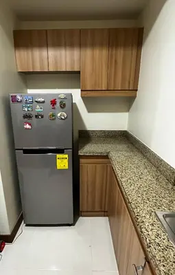 a kitchen with a stainless steel refrigerator and wooden cabinets at TresMariasCrib 3BR Unit at Pasig City Philippines in Manila