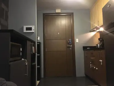 a kitchen with a wooden door and a refrigerator at Cozy Condo Near NAIA with WIFI, Pool and Balcony in Manila