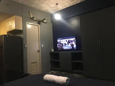 a bedroom with a flat screen tv and a bed at Cozy Condo Near NAIA with WIFI, Pool and Balcony in Manila