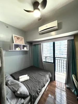 a bedroom with a bed with a ceiling fan and a balcony at Apartment in Air Residences, Makati with wifi, Netflix, pool, mall and more in Manila