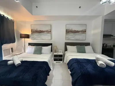 two beds in a bedroom with blue and white at Family KL Greenbelt Makati in Manila