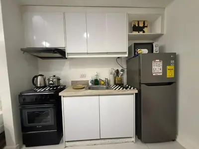 a small kitchen with a refrigerator and a sink at Family KL Greenbelt Makati in Manila