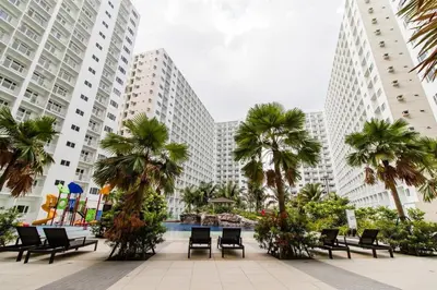 a courtyard with chairs and palm trees in front of tall buildings at Shore One Condotel At Mall of Asia, Philippines in Manila