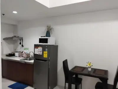 a kitchen with a table and a microwave on top of a refrigerator at Grand Riviera Suites, US Embassy Comfy, Affordable Studio in Roxas Blvd, Ermita Manila in Manila