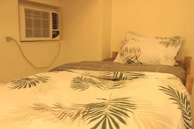 a bed with a white blanket with palm leaves on it at A2J Luxury Studio Near Venice Mall BGC Taguig in Manila