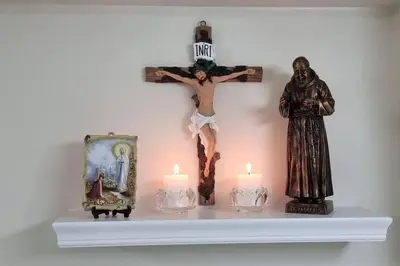 a cross on a shelf with candles and a statue at A cozy 2 bedroom condo in Metro in Manila