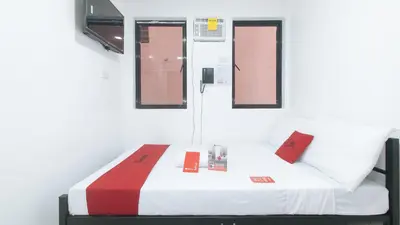a small room with a bed with red and white sheets at RedDoorz @ El Grande Inn Santa Cruz Manila in Manila