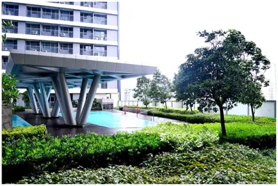 a building with a swimming pool next to a building at Iona Reign's Vacation Unit at FAME Residences in Manila