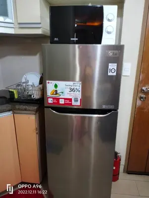 a stainless steel refrigerator with a microwave on top of it at CondoTel Pasay Newport City in Manila