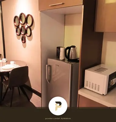 a small kitchen with a refrigerator and a table at FULLY FURNISHED STUDIO NEAR MOA in Manila