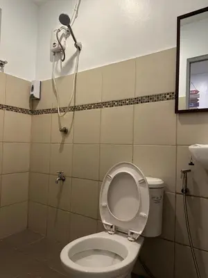a bathroom with a toilet with a shower in it at Aden Hotel in Manila