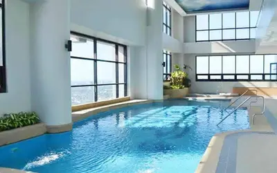 a large swimming pool with blue water in a building at Family Staycation with Pool in Manila