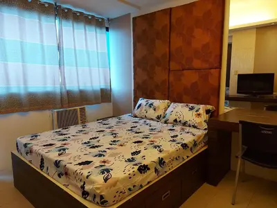 a small bedroom with a bed and a desk at Comfy Bunkbed with Pool in Manila