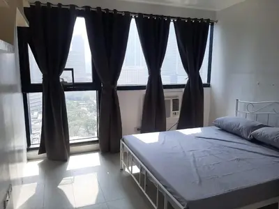 a bedroom with a bed and a large window at Comfy Bunkbed with Pool in Manila