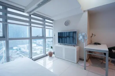 a white bedroom with a desk and a television at Uptown BGC Luxury 1br Suite with Fast Wifi in Manila