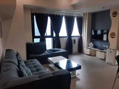 a living room with a couch and a table at Spacious 2 Bedroom Unit with Pool in Manila