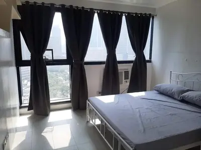 a bedroom with a bed and a large window at Spacious 2 Bedroom Unit with Pool in Manila