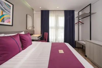 a bedroom with a purple and white bed and a desk at The Belamy House Managed by HII in Manila