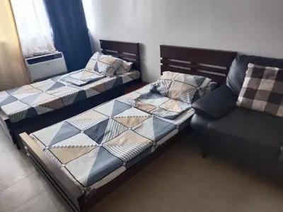 a bedroom with two beds and a couch at Family Staycation 2 with Pool in Manila