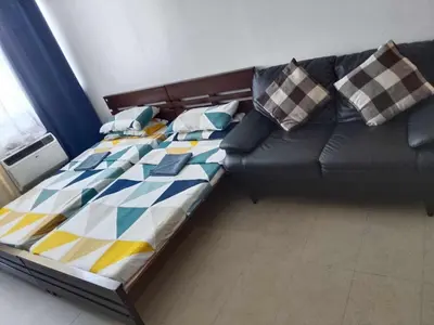 a bed in a living room with a black couch at Family Staycation 2 with Pool in Manila
