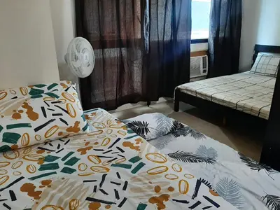 a bedroom with a bed with a comforter on it at Posh Beds with City View and Pools in Manila