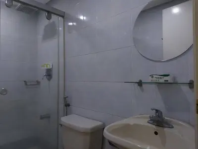 a bathroom with a toilet and a sink and a mirror at Posh Beds with City View and Pools in Manila