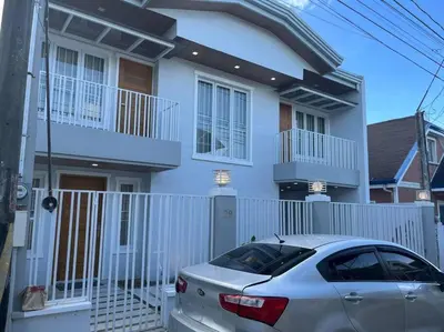 a white house with a fence and a car parked in front at Family Friendly Cozy Village Stay Sta Rosa Belair in Santa Rosa