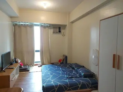 a bedroom with a blue bed and a television at Flair Towers STUDIO ROOMS Staycation in Manila