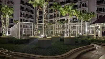 a row of palm trees with lights in front of a building at Sobere Unit in Manila