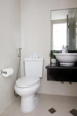 a white bathroom with a toilet and a sink at Stylish loft, 65 in UHDTV w Fast WiFi + Pool & Gym in Manila