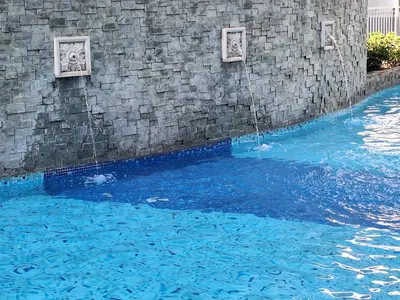 a swimming pool with blue water next to a stone wall at Best staycation at Shell residences in MOA complex in Manila