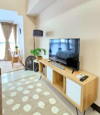 a living room with a flat screen tv on a entertainment center at Cosy Executive 1 BR Uptown Parksuites Ultra fast Internet in Manila