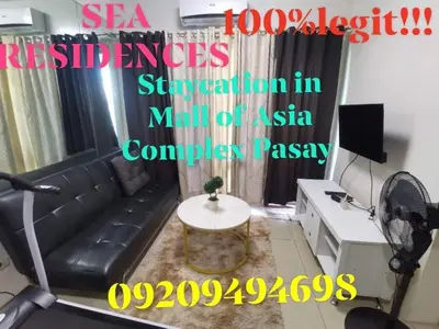 a living room with a black couch and a table at Sea Residences Staycation Tanya's Condo Pasay in Manila